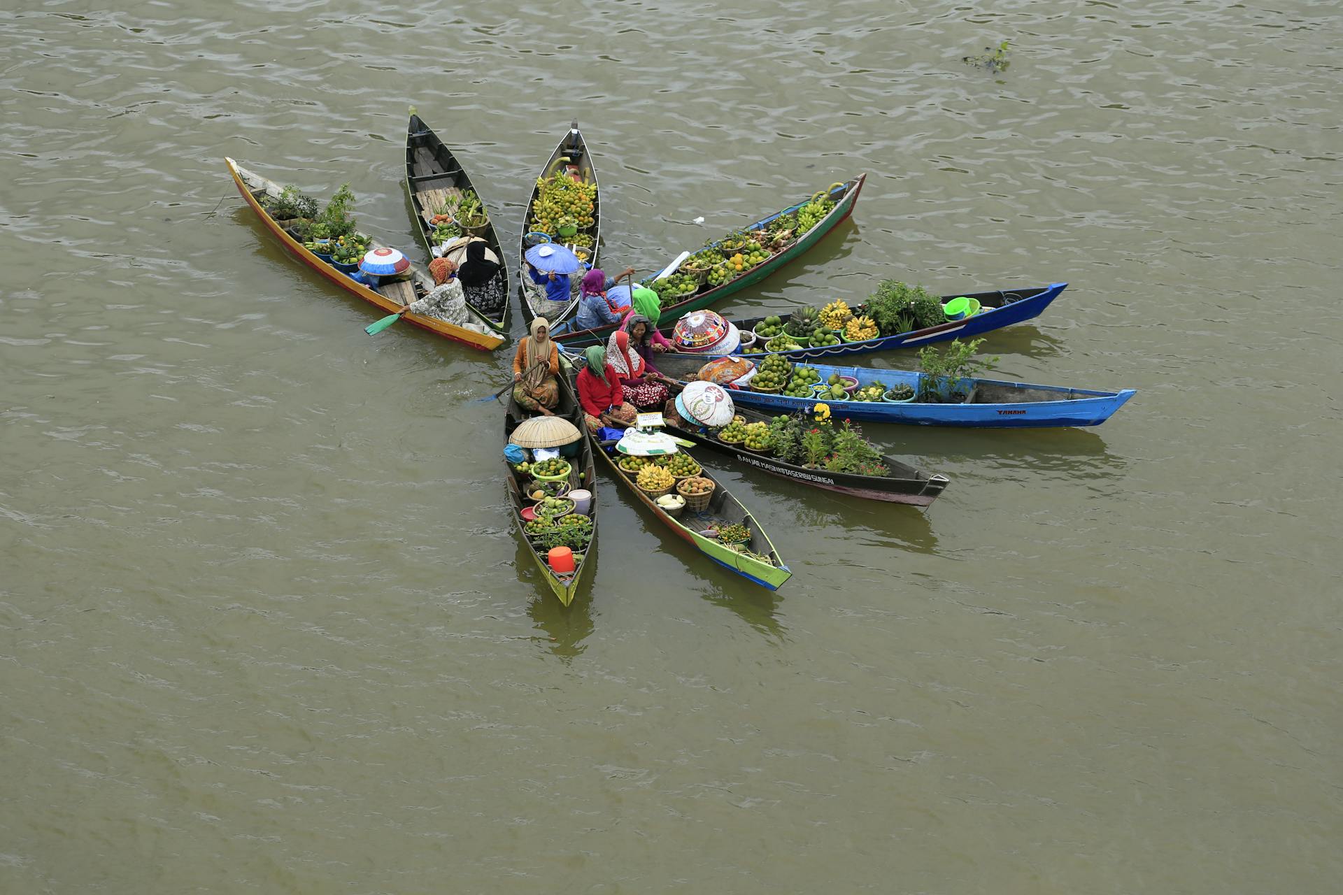 Aerial view of a floating market with colorful boats selling fresh produce.