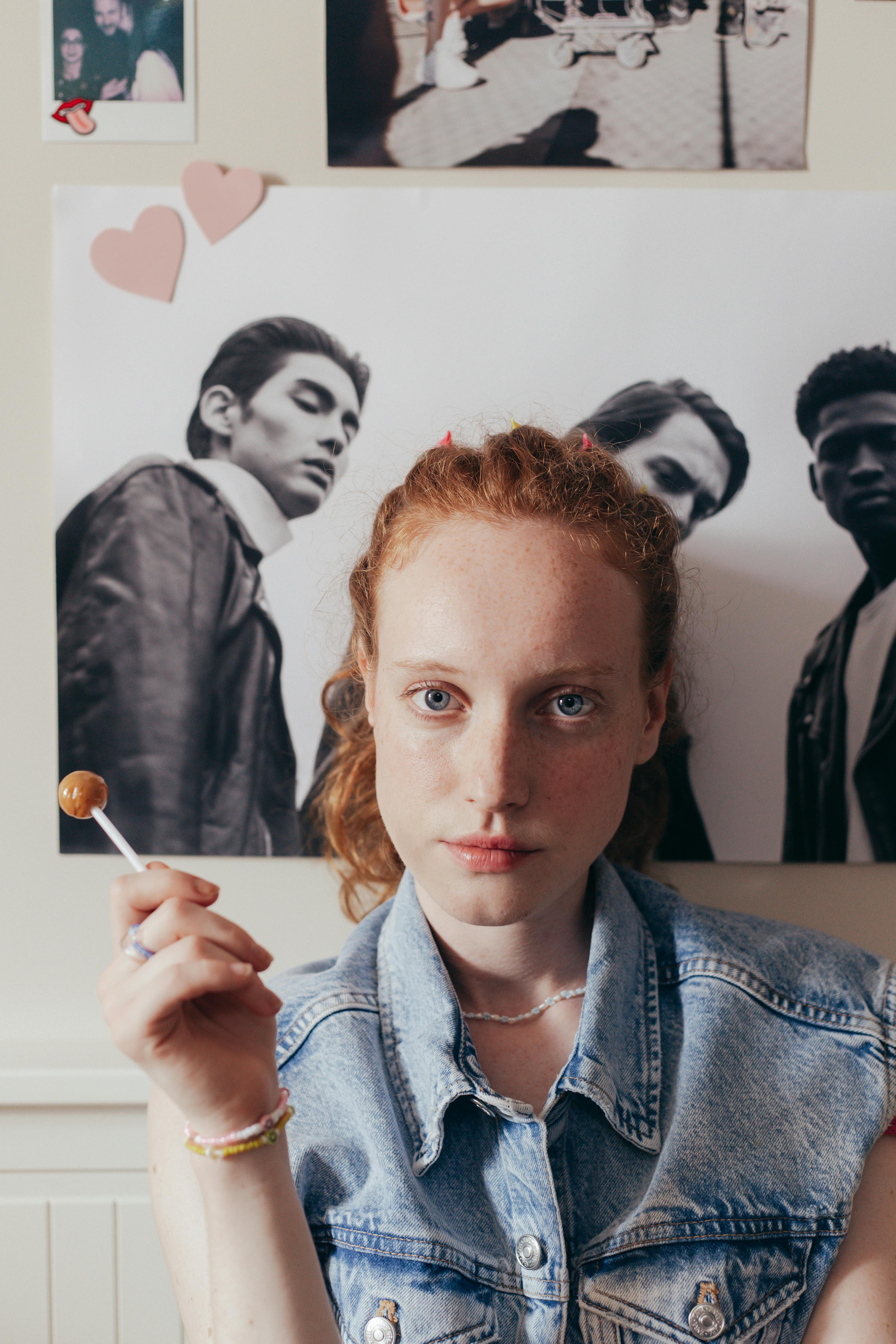 woman in denim vest holding a lollipop