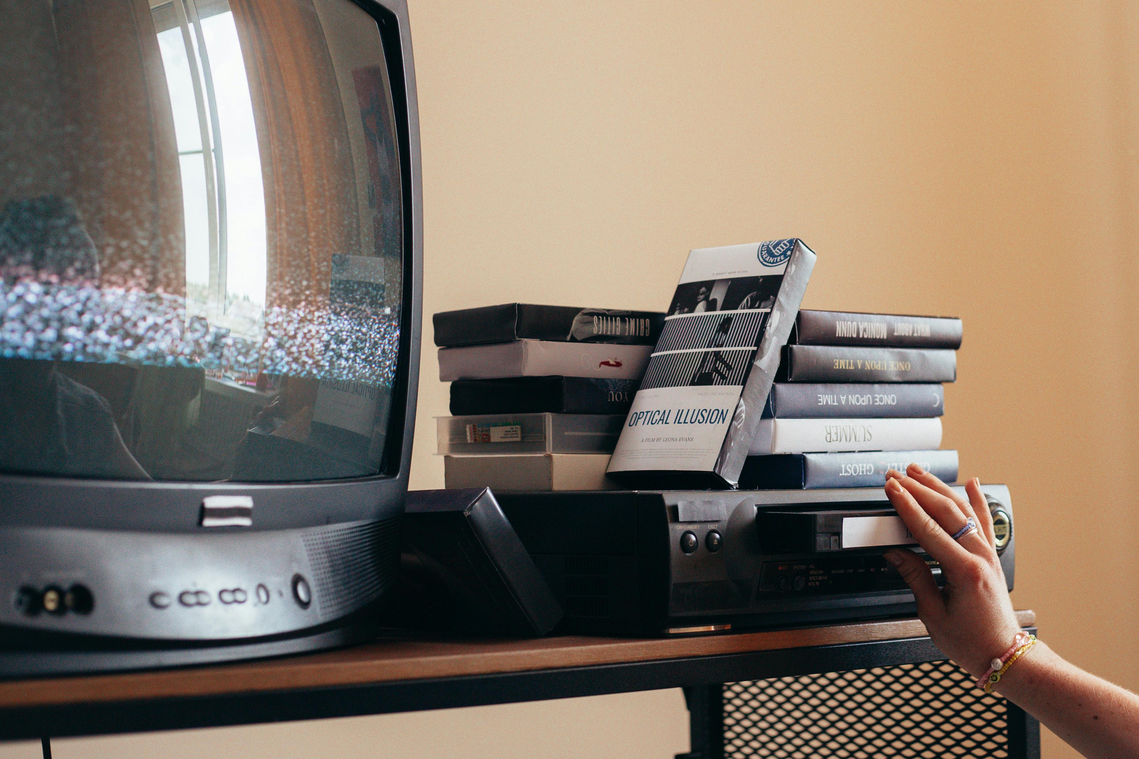 person putting a videotape on a vhs player