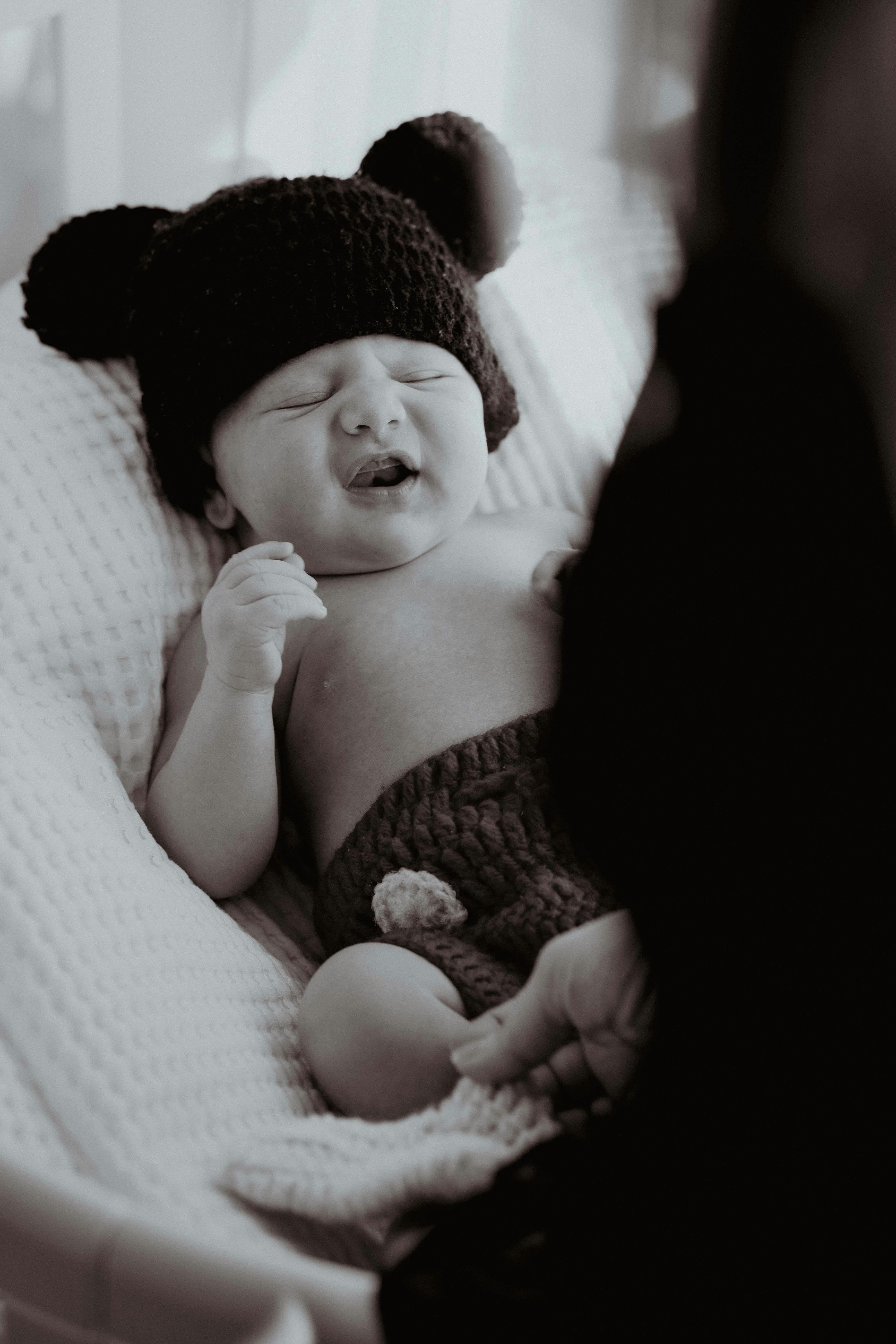 A tender black and white portrait of a baby in a knit costume sleeping peacefully.