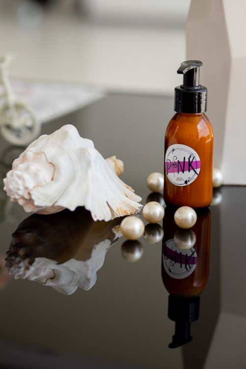 Free Luxurious skincare setup featuring pump bottle, seashell, and pearls on reflective surface. Stock Photo