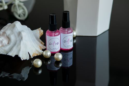Free A stylish still life scene featuring pink cosmetic bottles, a white shell, and pearls. Stock Photo