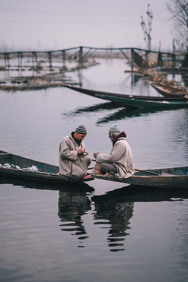 Two Men Sitting In The Canoes On The River