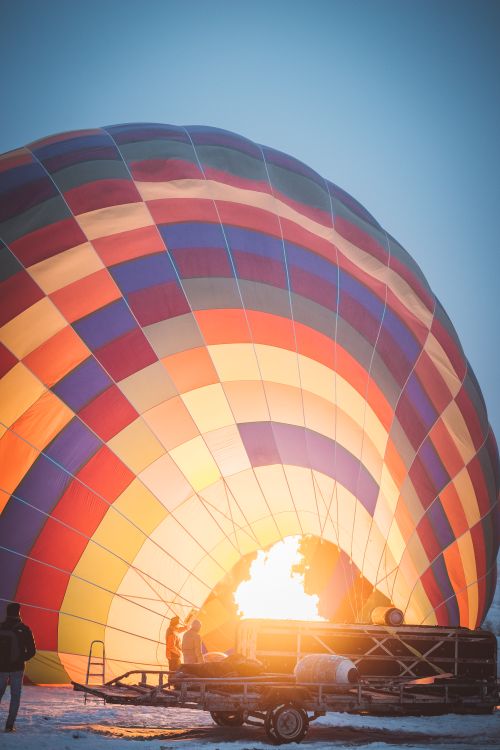 Free A vibrant hot air balloon inflating at sunrise on a snowy day, creating a colorful scene. Stock Photo
