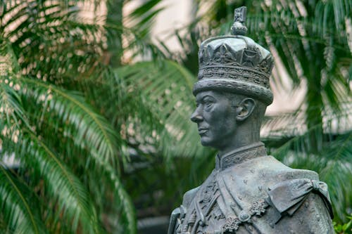 Male Statue Near Green Palm Trees at Daytime