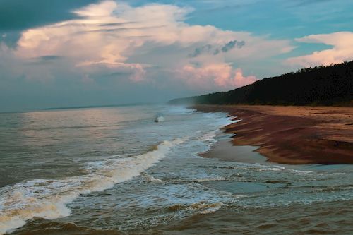 Free Serene beach view in Sri Lanka with waves and dramatic clouds at twilight. Stock Photo