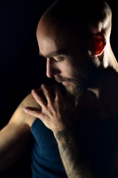 Dramatic close-up portrait of a bald man with beard in a studio setting.