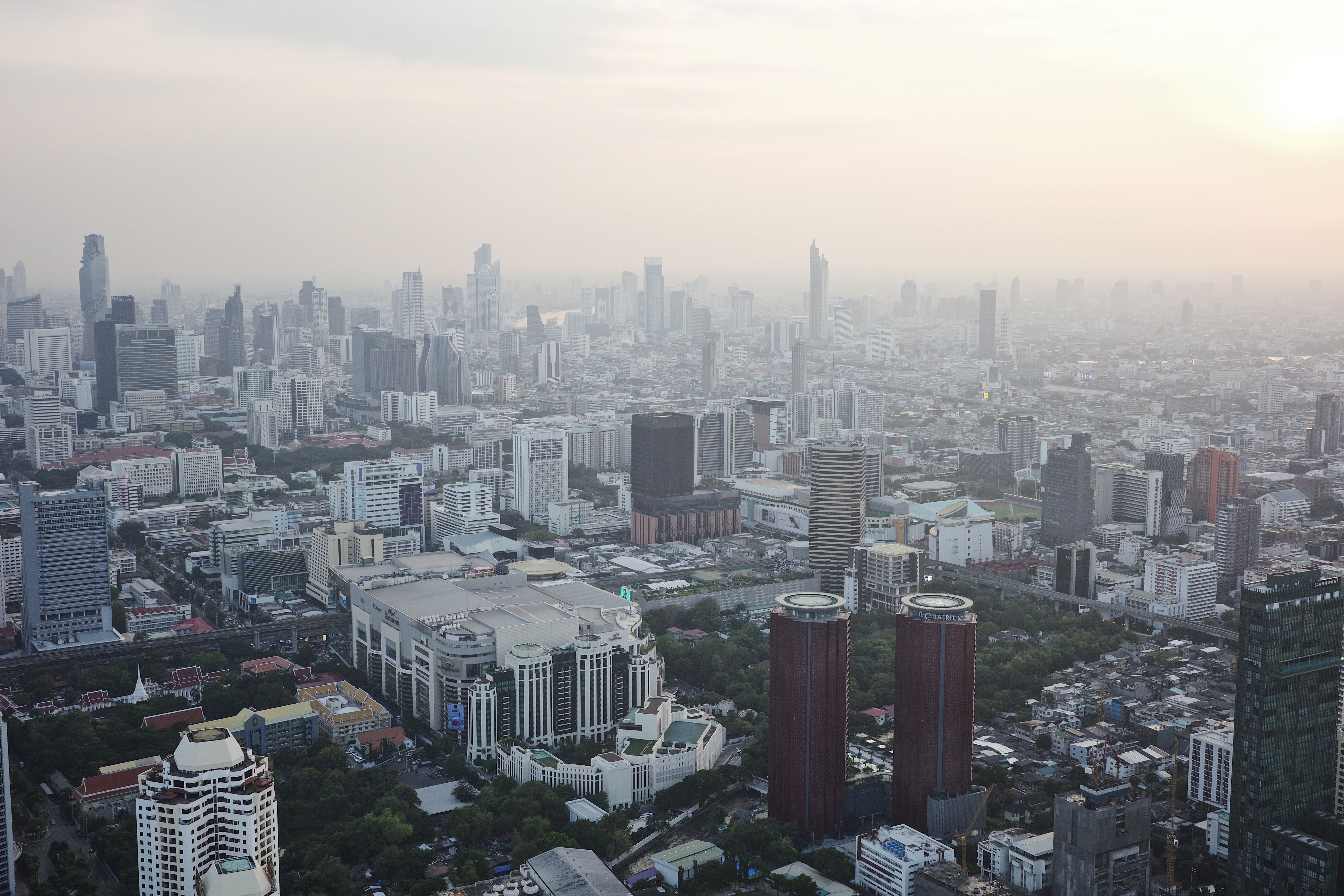 Dramatic aerial view of Bangkok skyline, highlighting the modern urban landscape at sunset.