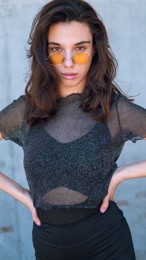 Free Confident woman in trendy outfit and sunglasses striking a bold pose with hands on hips. Stock Photo