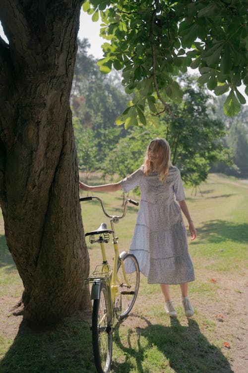 Teenage Girl in Long Dress in Park with Bicycle 