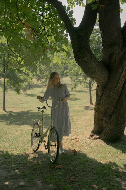 Girl in Long Dress Pushing Bicycle in Park