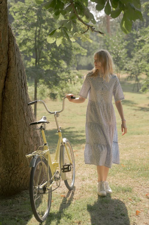 Teenage Girl in Long Dress Holding Bicycle in Park