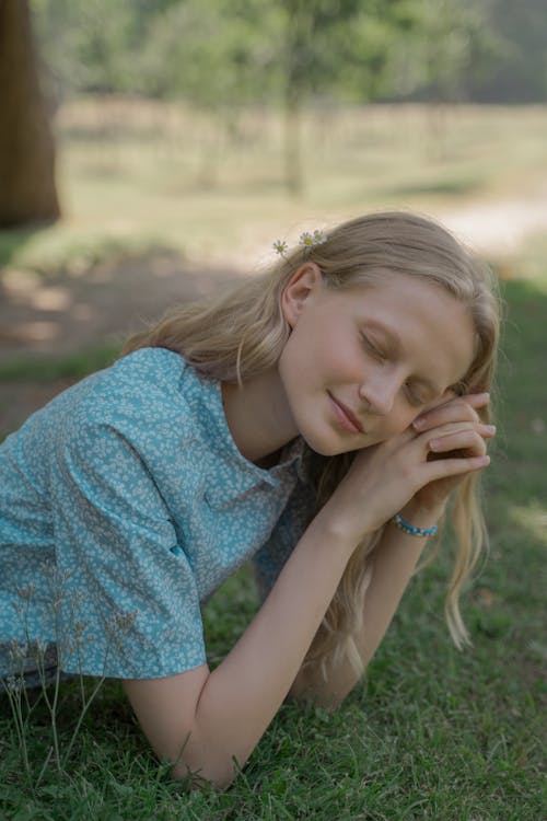 Portrait of Blond Haired Girl Lying on Front on Grass