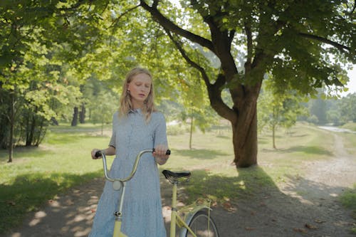 Blond Haired Girl Holding Bicycle