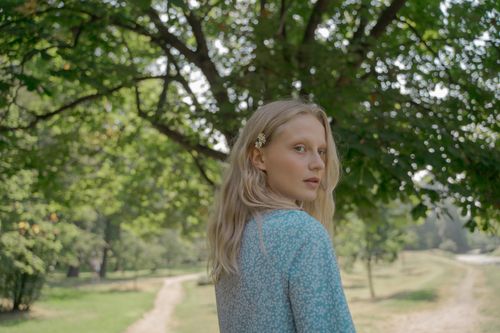 Free Portrait of a teenager in a park during summer, with lush greenery and soft lighting. Stock Photo