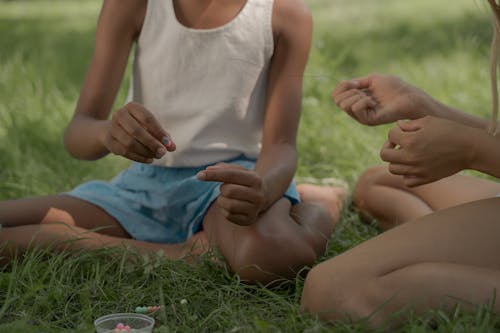 Girls Sitting on Grass Making Beads Necklace