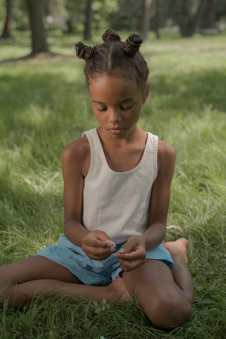 Girl Sitting On Grass Making Beads Necklace