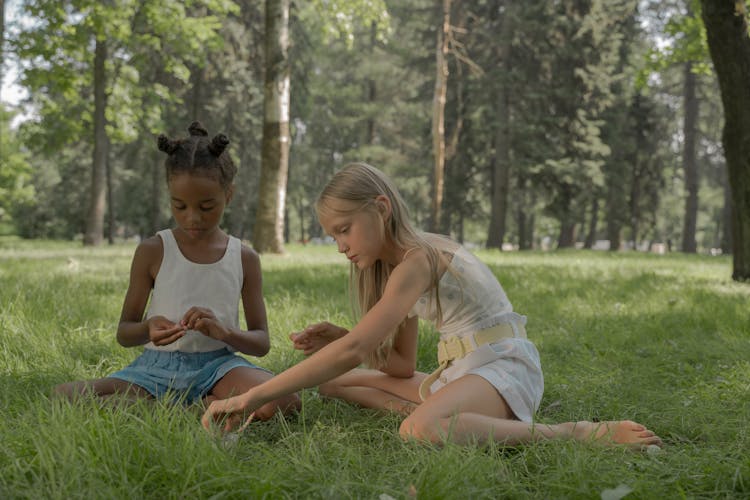 Girls Sitting On Grass Making Beads Necklace