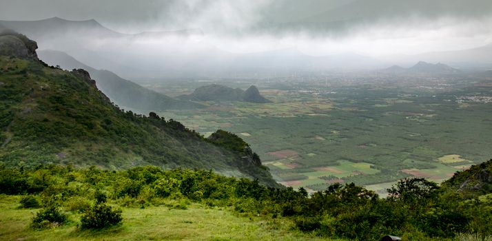 A breathtaking aerial view of a misty landscape with mountains and verdant fields.