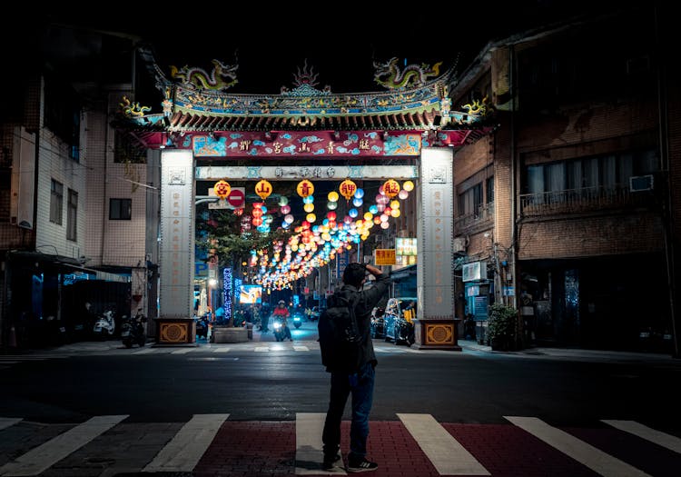 Back View Of A Man Standing On Pedestrian Lane During Night Time