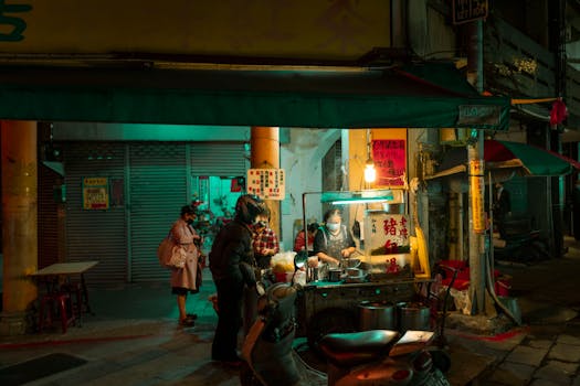 Street vendor cooking and serving food at night market with vibrant lights.