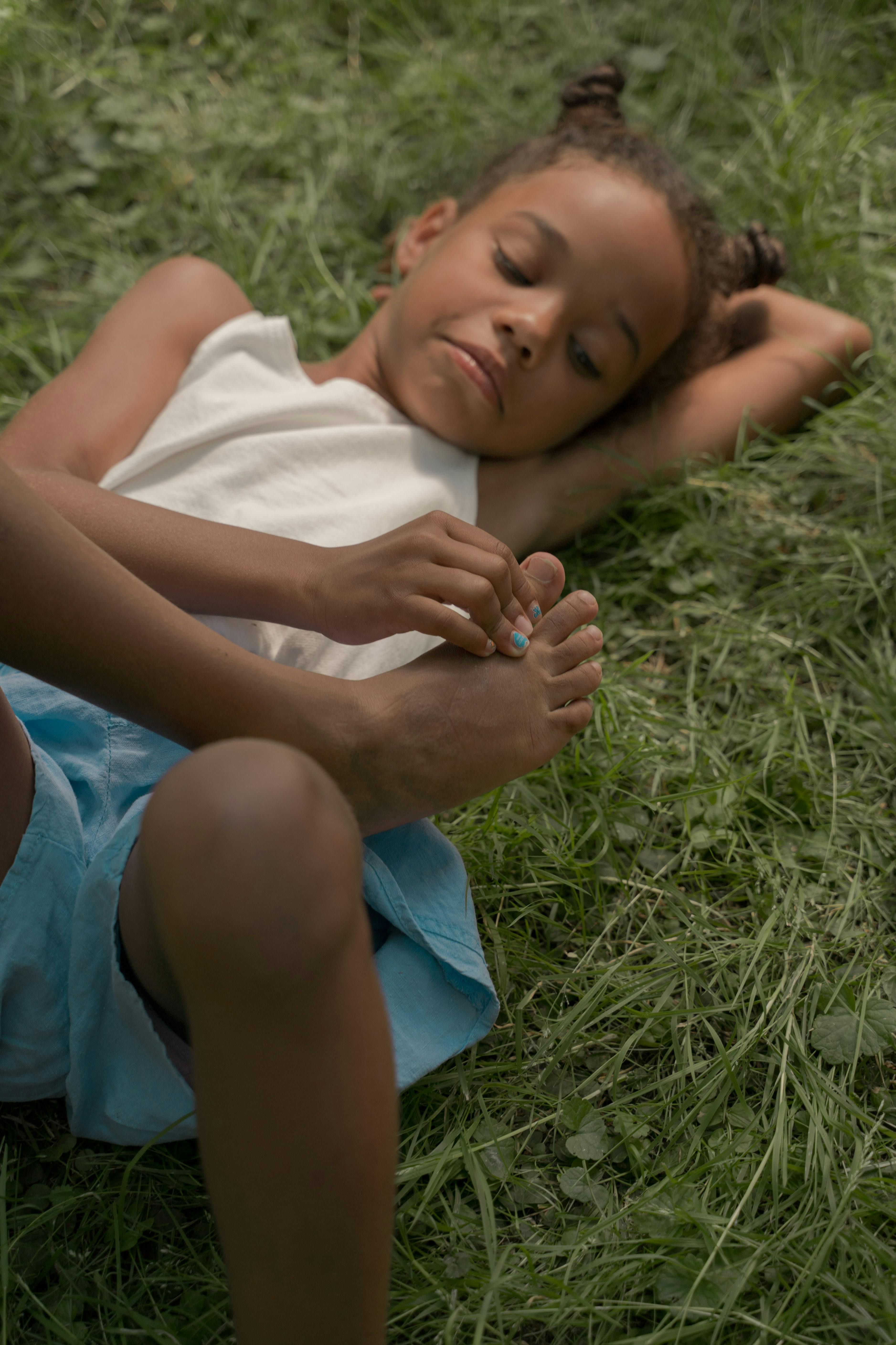 cute girl laying on grass and looking at her toes