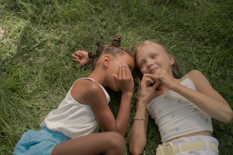 Two Teenage Girls Laying On Green Grass