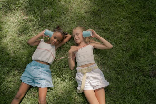 Two Girls Laying on Lawn and Playing