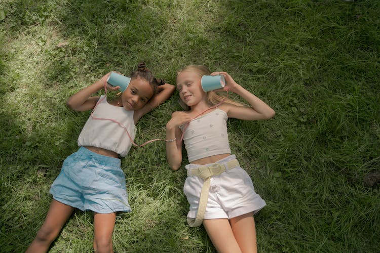 Two Girls Laying On Lawn And Playing