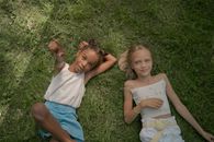 Girls Relaxing on Grass Pointing Up