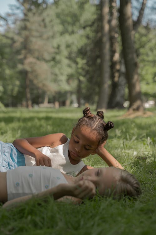 Two Teenage Girls Laying on Lawn in Park on Summer Sunny Day