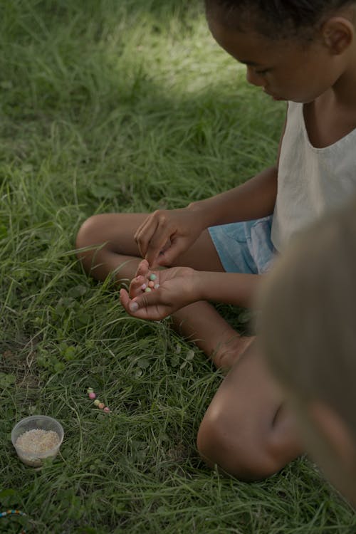 Girls Sitting on Grass Making Beads Bracelets