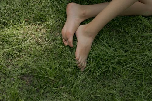 Free Close-up of bare feet relaxing on lush green grass, depicting tranquility. Stock Photo