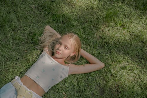 Free Blond Teenage Girl Laying on Green Grass Stock Photo