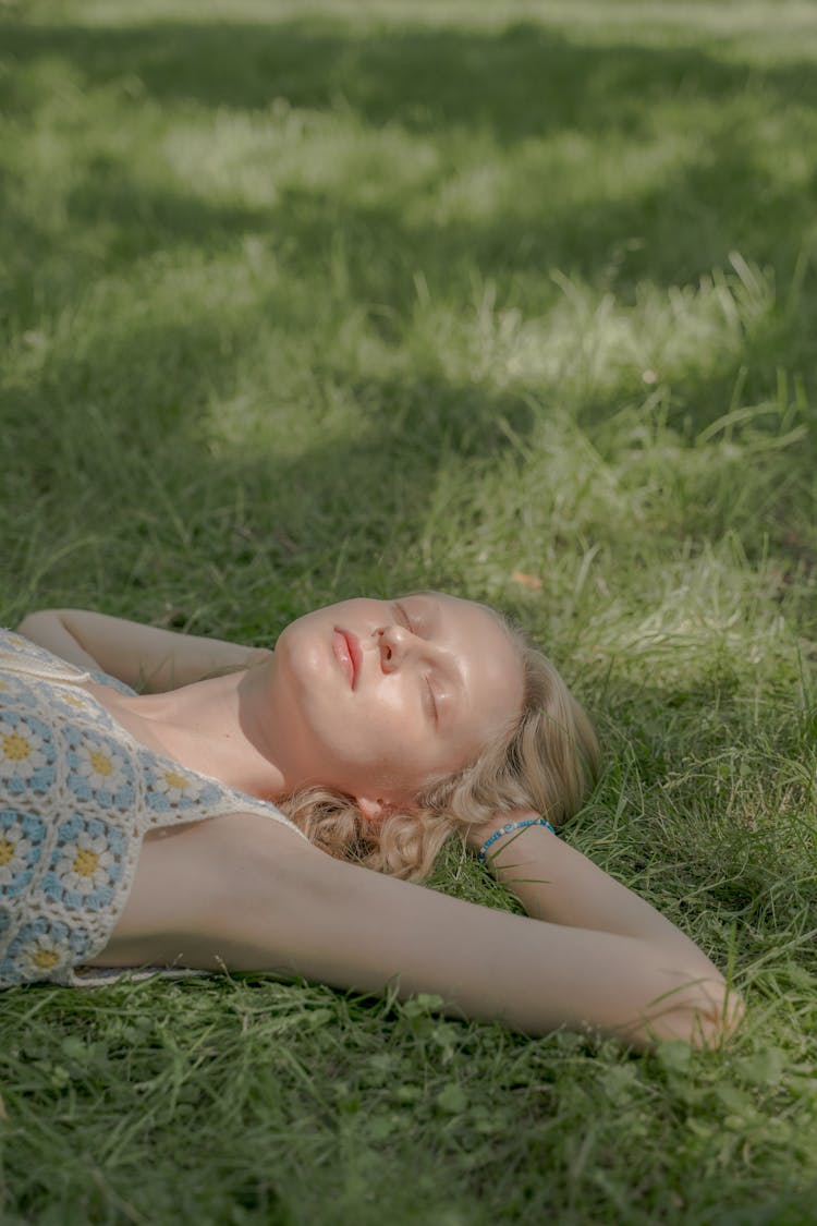 Teenage Girl Laying On Grass With Eyes Closed And Hands Behind Head