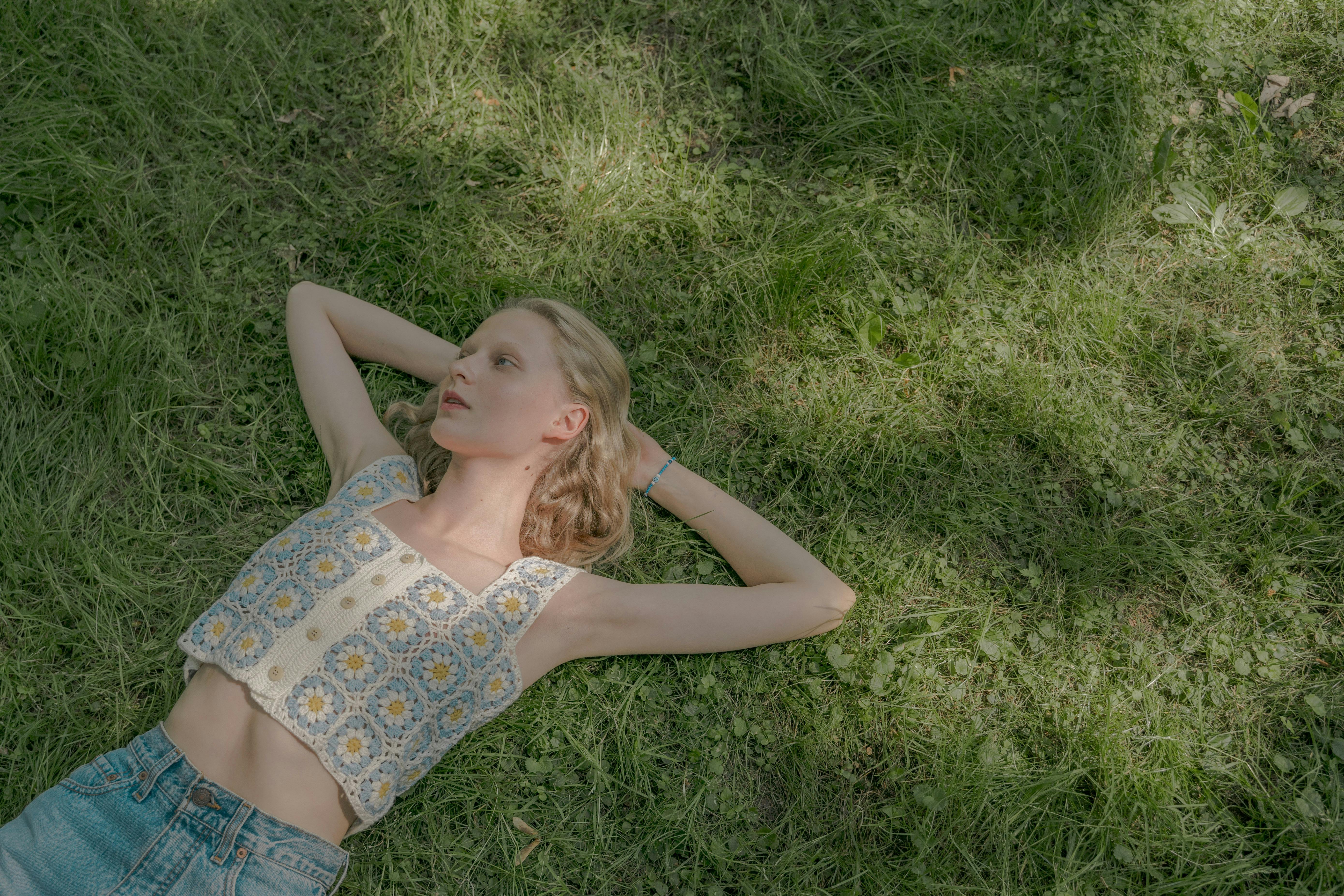 blond young woman laying on lawn on summer sunny day