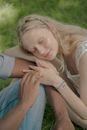 Young Woman with Long Blond Hair Resting Her Head on Unrecognizable Male Hand