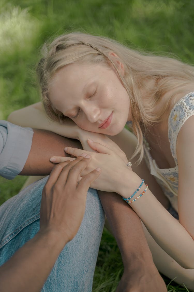 Young Woman With Long Blond Hair Resting Her Head On Unrecognizable Male Hand