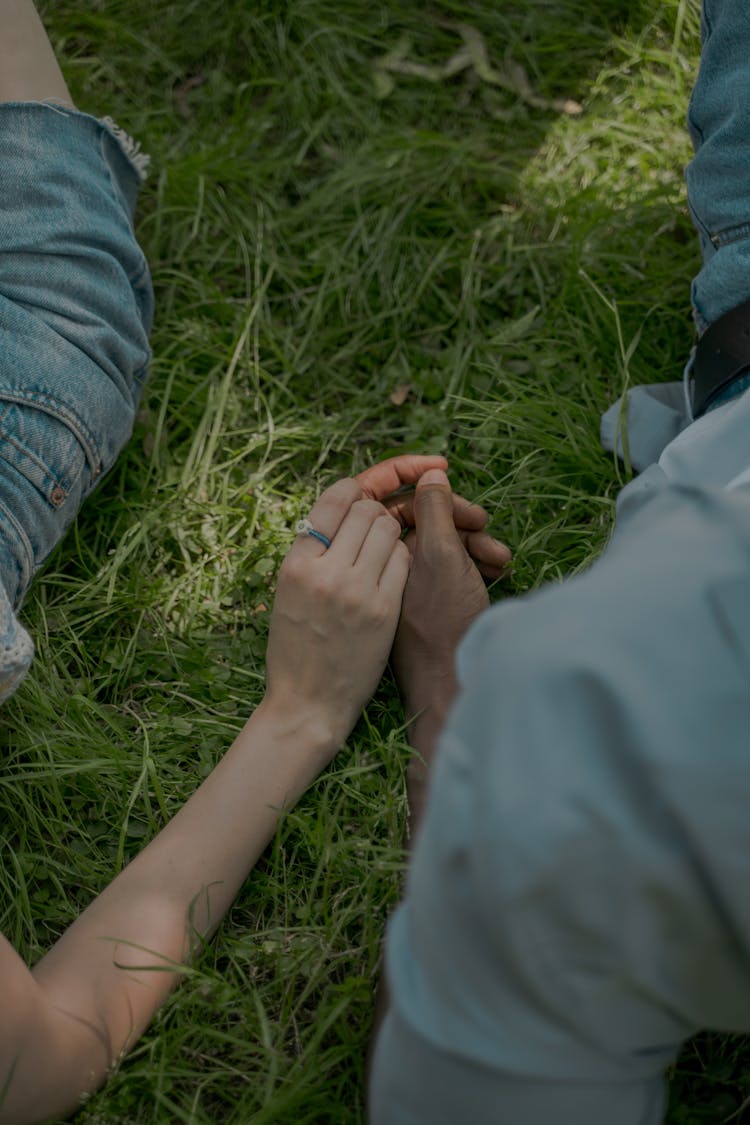 Hands Of Man And Woman Laying On The Grass