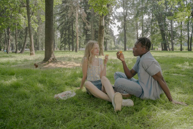 Man And Woman Sitting On The Grass And Eating Peaches