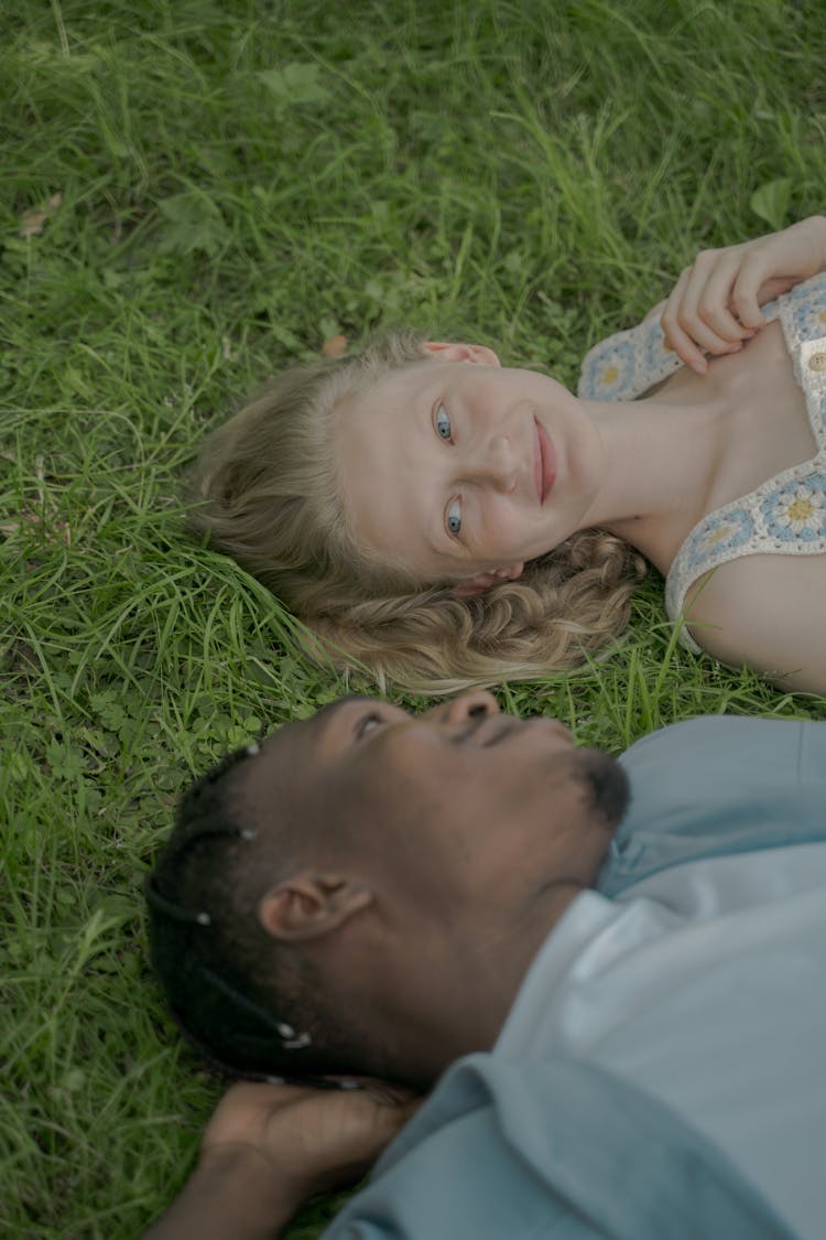 Man And Woman Laying On The Grass And Looking At Each Other