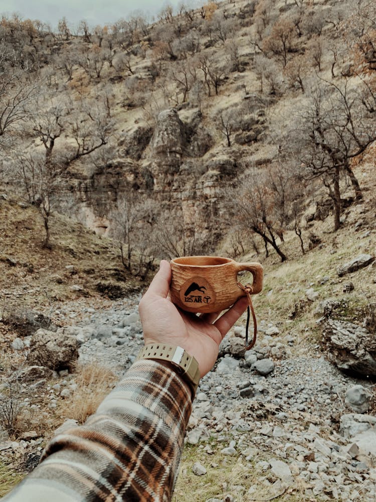 A Person Holding A Mug In A Desert