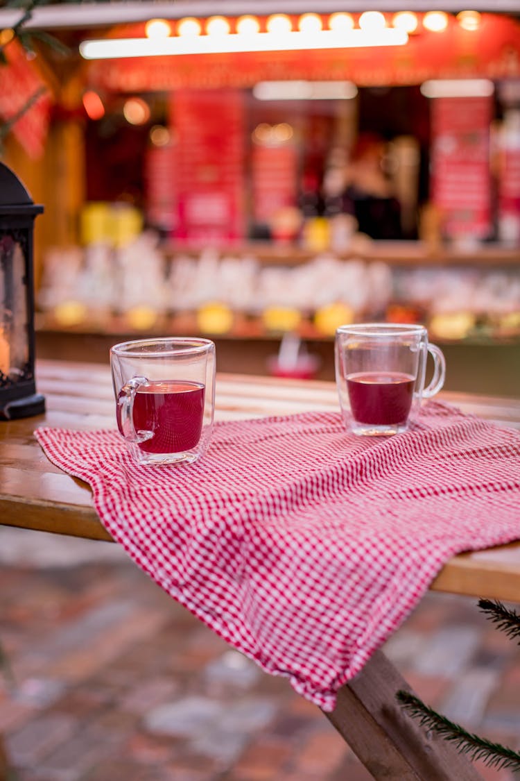 Clear Teacups On A Checkered Cloth On A Brown Wooden Table