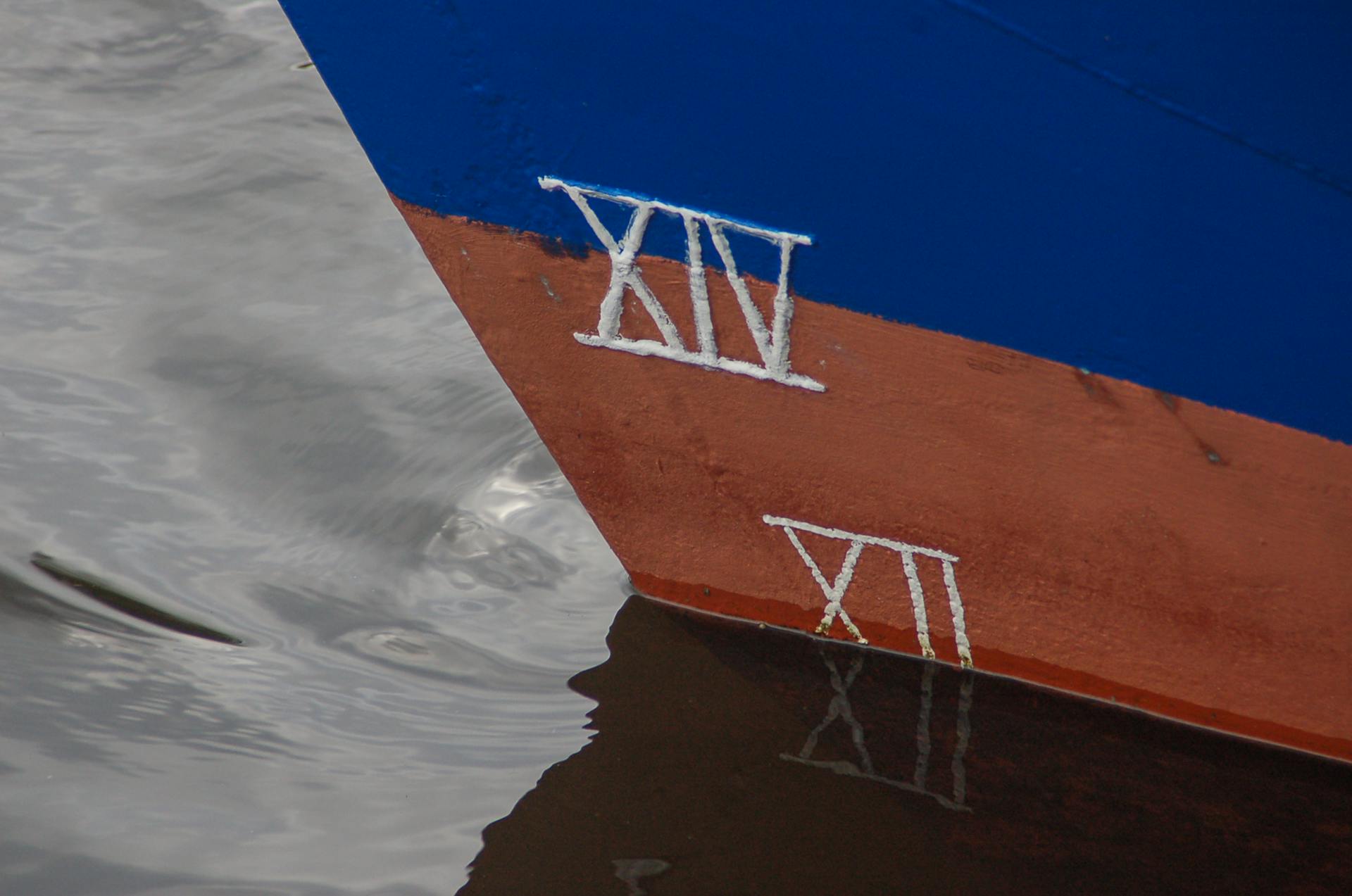 Detailed view of a colorful boat hull marked with Roman numerals at the waterline.