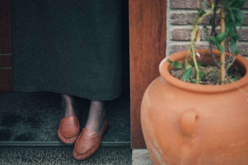 Free Detailed view of red slip-on shoes paired with a rustic terracotta plant pot. Stock Photo