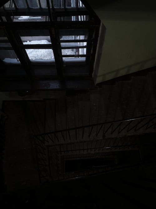 Concrete Stairs with Metal Railings and Window Inside a Dark Building 