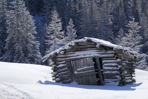Free A picturesque log cabin covered in snow, set in the winter woods of Trentino-Alto Adige, Italy. Stock Photo