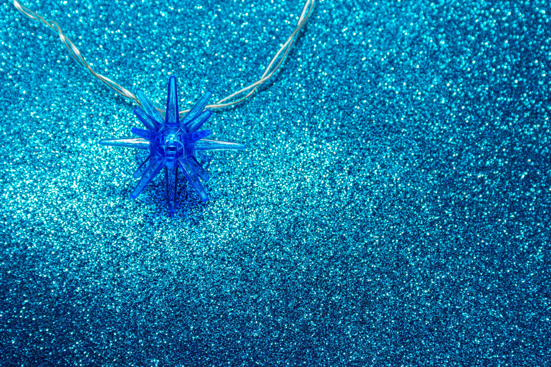 Close-up of a blue crystal pendant on a glittery background, perfect for jewelry themes.