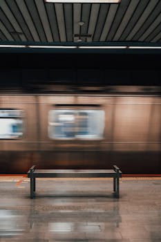 Blurred motion of Istanbul metro train passing through a station with a bench in the foreground.