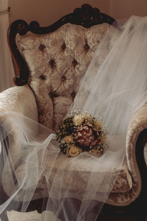 Free Beautiful bridal bouquet with veil on a vintage upholstered chair, perfect for romantic settings. Stock Photo